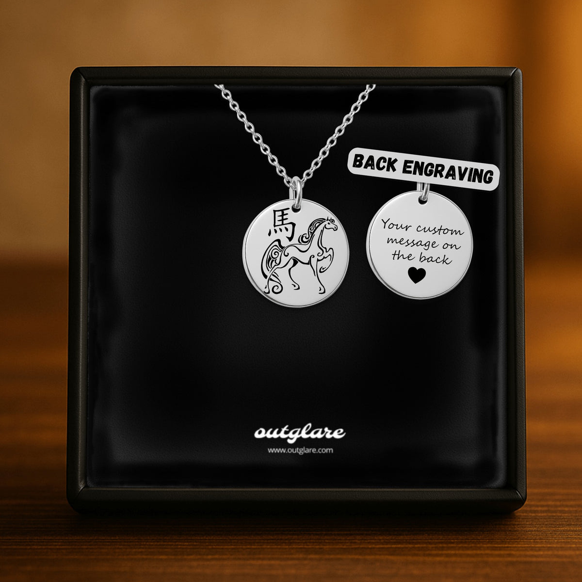 A silver necklace displayed inside a black presentation box, featuring two round engraved pendants: one with a horse design and one with placeholder text for custom message engraving on the back. The box shows the brand name 'outglare'.